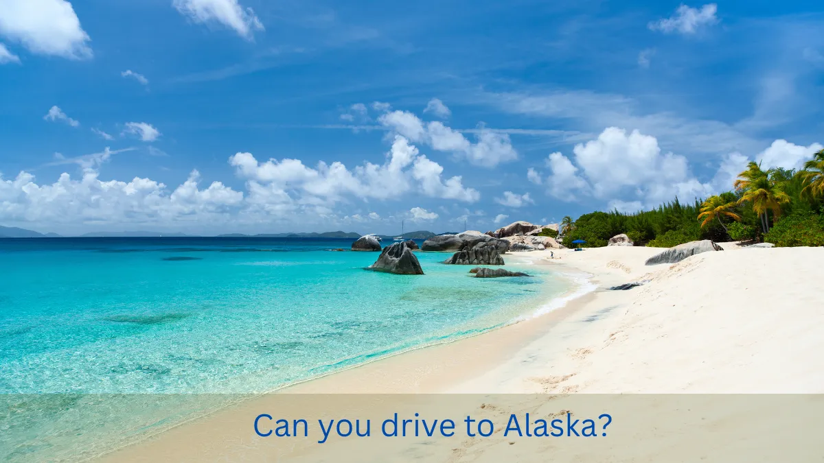 Can you drive to Alaska? Image of a tropical beach with clear blue water, sunny skies, and rocky formations along the shoreline, symbolizing the surprising contrast to what most people might expect when considering a road trip to Alaska.