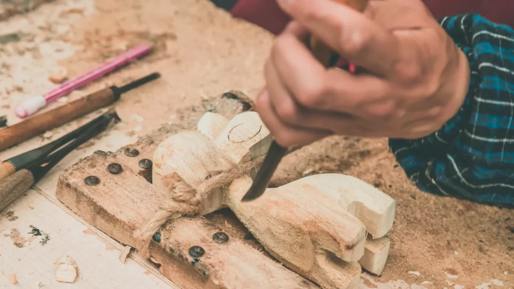 A craftsman carving a wooden figure using the Best Wood for Carving, focusing on detailed work with chisels.